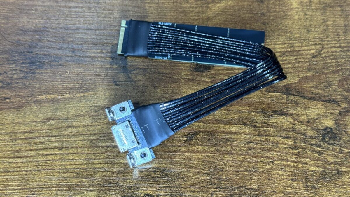 M.2→OCuLink変換アダプタ(ケーブル型)。M.2端子から平たい帯状のケーブルが伸び、その先に金具付きのOCuLinkポートが付いている
