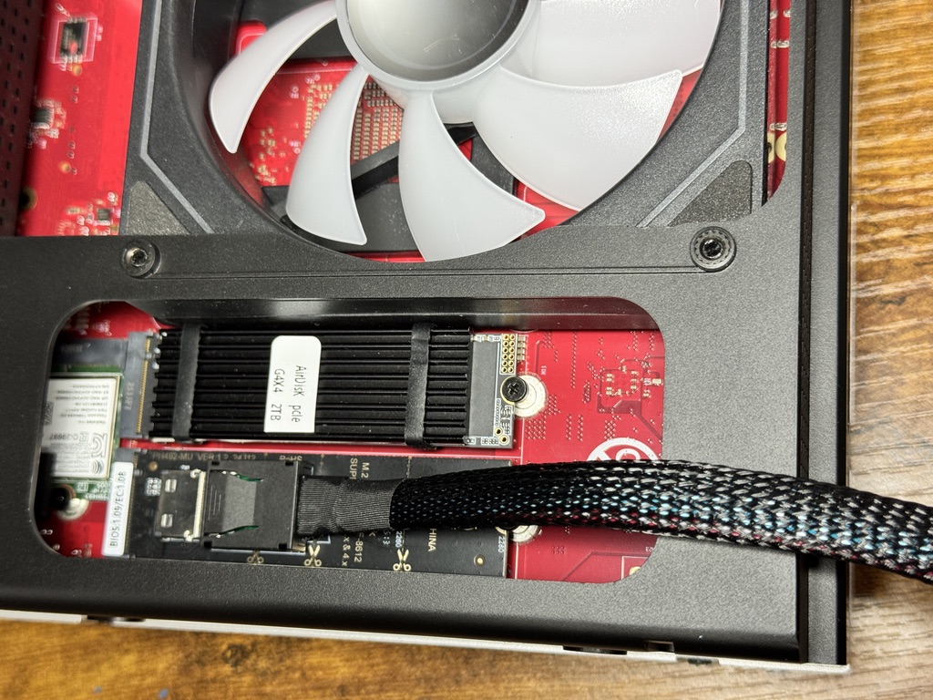 ミニPCの底面カバーを外した内部。M.2スロットに取り付けた変換アダプタから、太い編組ケーブルが本体の外へ伸びている