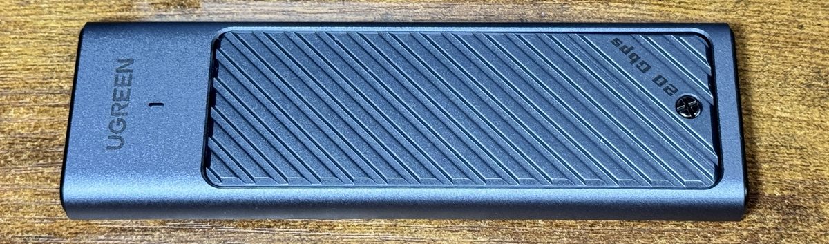 入れ替え前のケース。ふたに「20 Gbps」と刻まれています。右端の丸いものが、開けるときに外すねじです。